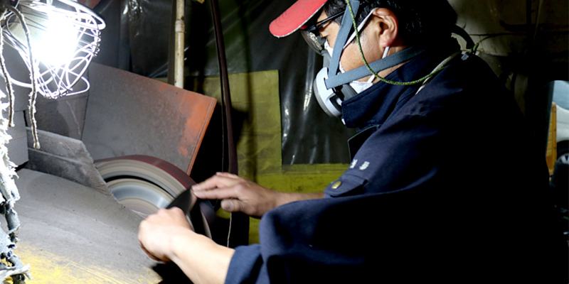 湿式のベルトサンダーで包丁の形と厚みを整えます